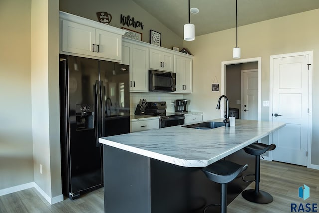 kitchen featuring sink, black appliances, pendant lighting, white cabinets, and an island with sink