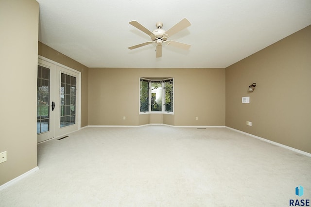 spare room featuring ceiling fan, light colored carpet, and french doors