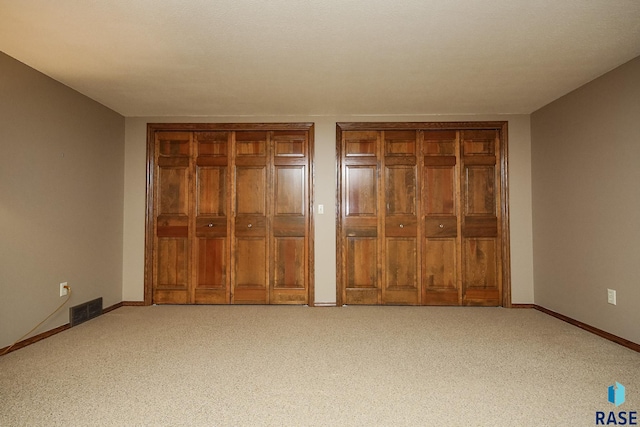 unfurnished bedroom with light carpet and multiple closets