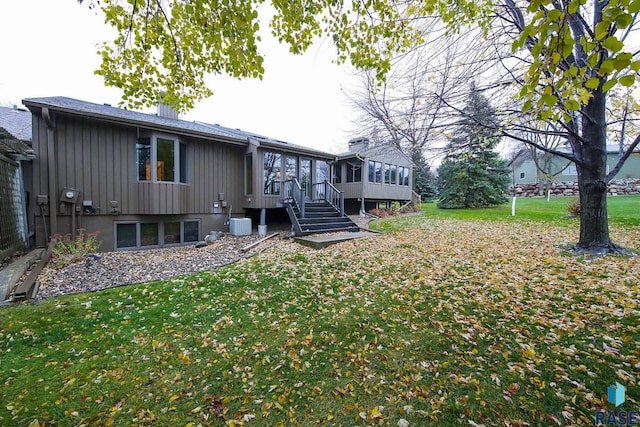 rear view of house featuring a sunroom, a yard, and cooling unit