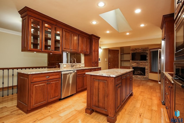 kitchen with dishwasher, a center island, light hardwood / wood-style flooring, and a brick fireplace