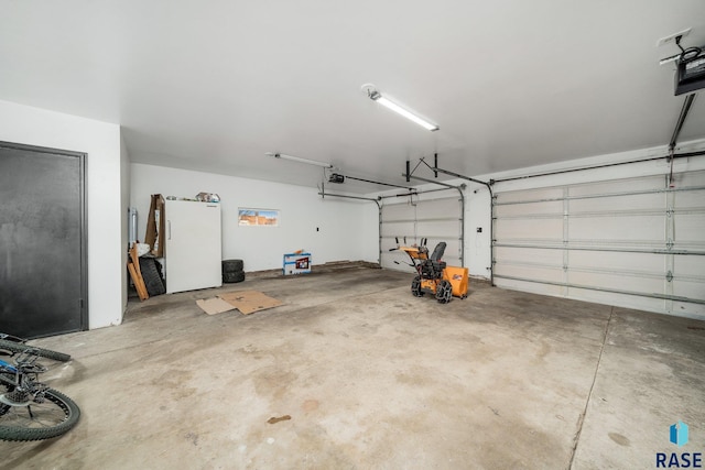 garage featuring white refrigerator and a garage door opener