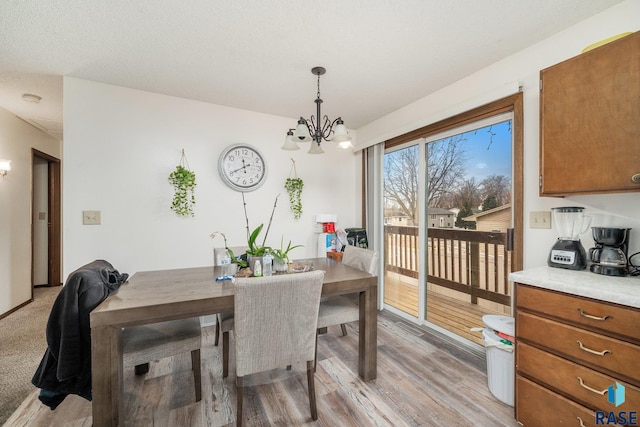 dining space with light hardwood / wood-style flooring, a chandelier, and a textured ceiling