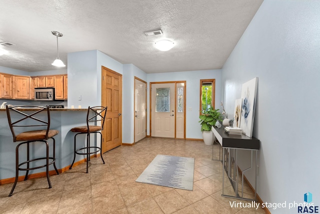 foyer featuring light tile patterned floors and a textured ceiling