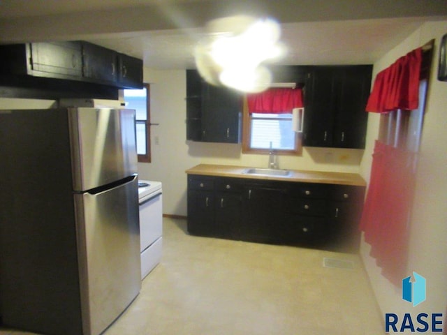 kitchen featuring white electric range oven, stainless steel refrigerator, and sink