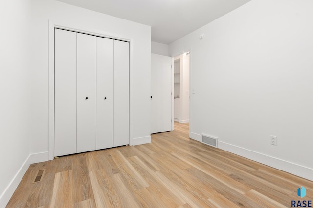 unfurnished bedroom with light wood-type flooring and a closet