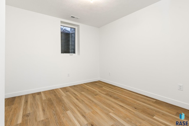 spare room with a textured ceiling and light wood-type flooring