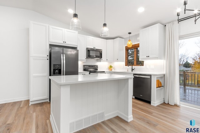 kitchen with white cabinets, stainless steel appliances, vaulted ceiling, and a kitchen island