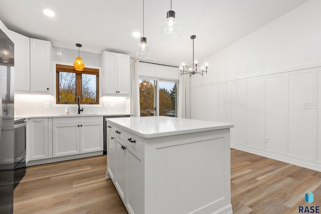 kitchen with a center island, sink, hanging light fixtures, light hardwood / wood-style floors, and white cabinetry