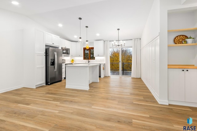 kitchen featuring a kitchen island, stainless steel appliances, decorative light fixtures, and light wood-type flooring