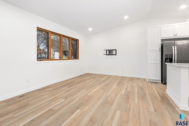 interior space with light wood-type flooring and vaulted ceiling