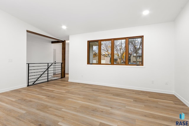 spare room with vaulted ceiling and light hardwood / wood-style flooring