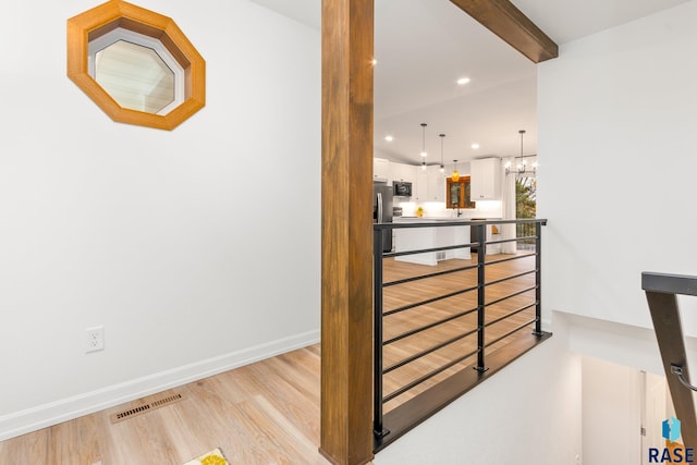 interior space featuring beamed ceiling, a chandelier, and light hardwood / wood-style flooring