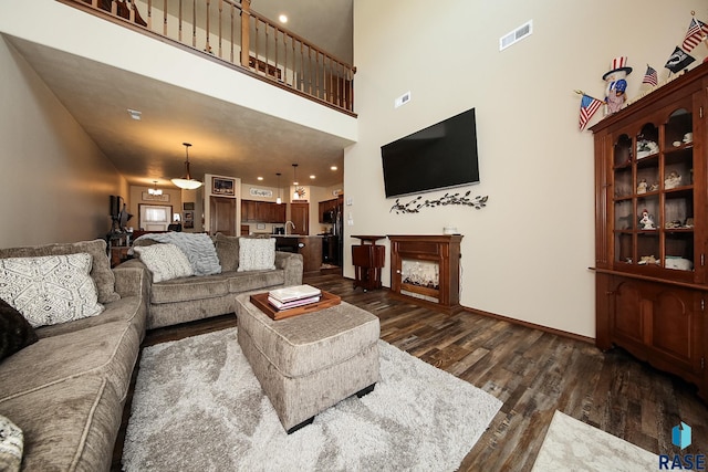 living room with sink, dark wood-type flooring, and a high ceiling