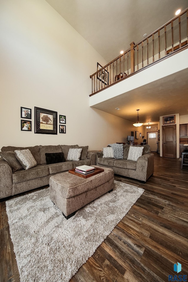 living room featuring a towering ceiling and dark hardwood / wood-style flooring