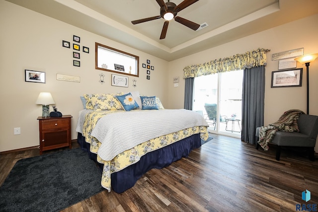 bedroom featuring access to exterior, a raised ceiling, ceiling fan, and dark wood-type flooring