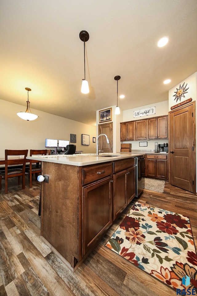 kitchen featuring sink, dark wood-type flooring, hanging light fixtures, and black dishwasher