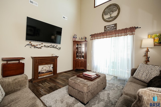 living room featuring a healthy amount of sunlight, dark hardwood / wood-style flooring, and a high ceiling