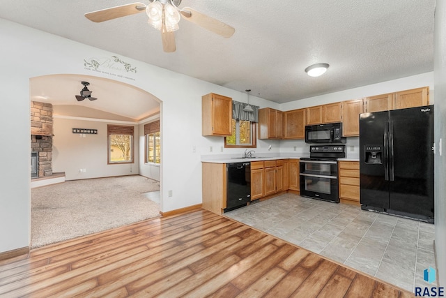 kitchen featuring lofted ceiling, black appliances, sink, light hardwood / wood-style flooring, and a textured ceiling