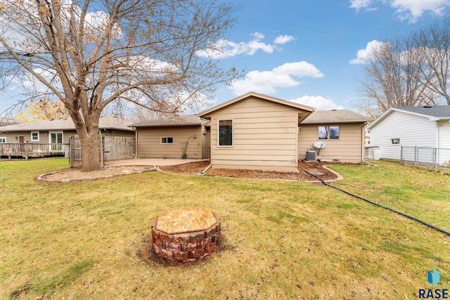 rear view of house with a patio, a fire pit, central AC unit, and a lawn