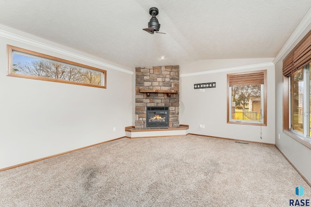 unfurnished living room with carpet, lofted ceiling, ornamental molding, a fireplace, and a textured ceiling