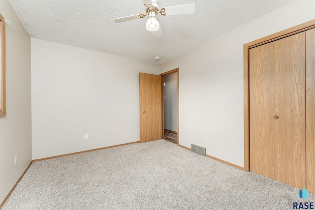 unfurnished bedroom featuring ceiling fan, a textured ceiling, and light carpet