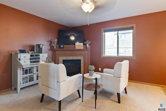 living area featuring a tiled fireplace, ceiling fan, and light colored carpet