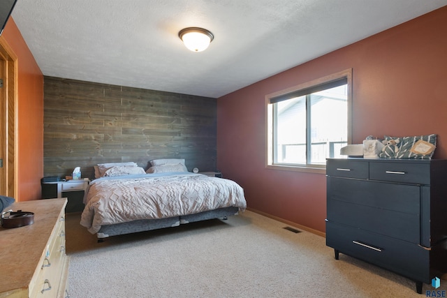 bedroom with carpet, a textured ceiling, and wooden walls