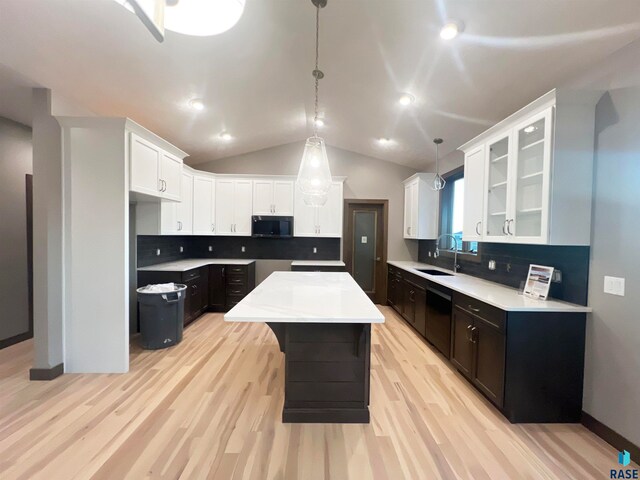 kitchen with lofted ceiling, a center island, hanging light fixtures, black dishwasher, and white cabinets