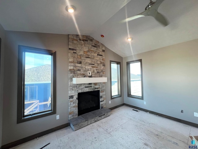 unfurnished living room with ceiling fan, a stone fireplace, and vaulted ceiling