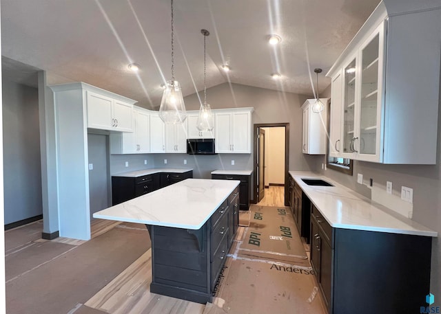 kitchen featuring a kitchen island, decorative light fixtures, white cabinetry, lofted ceiling, and sink