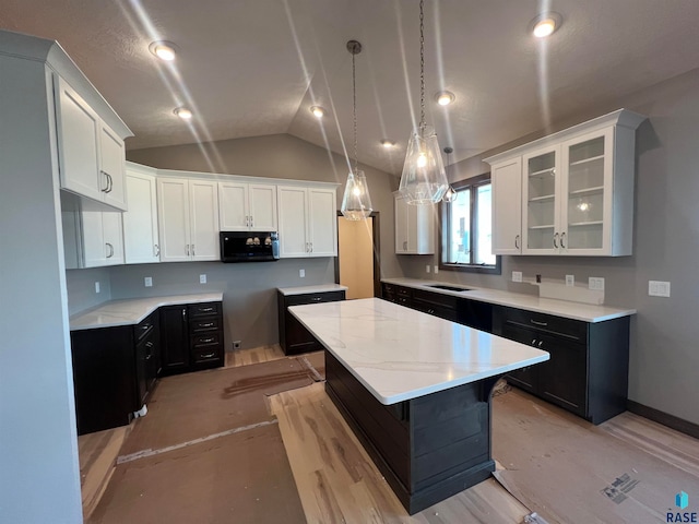 kitchen featuring white cabinetry, a kitchen island, sink, and lofted ceiling