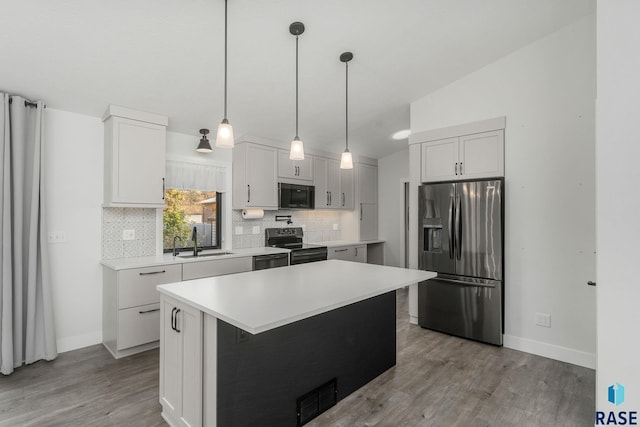 kitchen with stainless steel appliances, vaulted ceiling, a kitchen island, light hardwood / wood-style flooring, and white cabinetry