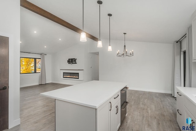 kitchen with pendant lighting, white cabinets, lofted ceiling with beams, light hardwood / wood-style flooring, and a kitchen island