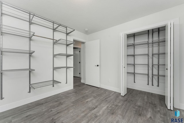 unfurnished bedroom with a textured ceiling, a closet, and dark wood-type flooring