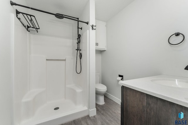 bathroom featuring vanity, a textured ceiling, a shower, hardwood / wood-style flooring, and toilet