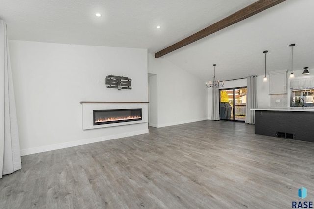 unfurnished living room featuring a chandelier, hardwood / wood-style floors, lofted ceiling with beams, and sink