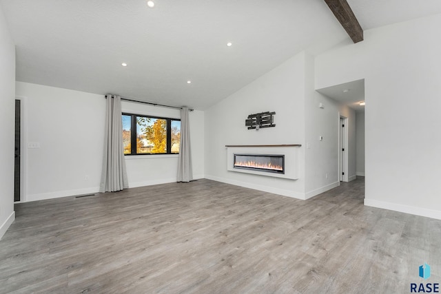 unfurnished living room with beamed ceiling, light hardwood / wood-style floors, and high vaulted ceiling