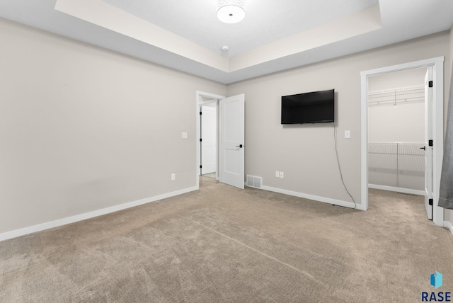 unfurnished bedroom featuring a spacious closet, a closet, and light colored carpet