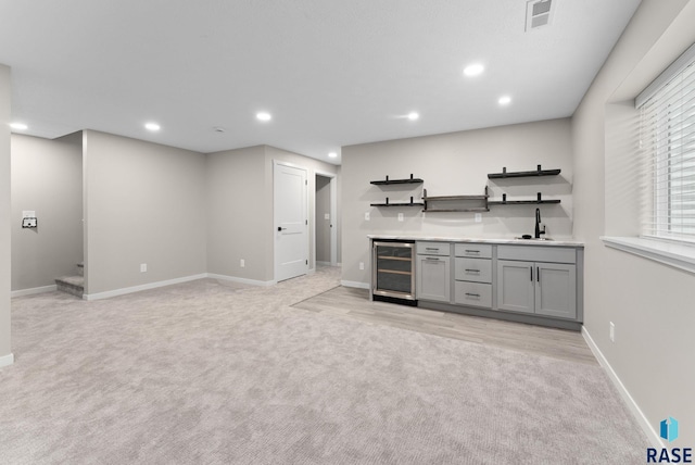 bar featuring wine cooler, light carpet, sink, and gray cabinets