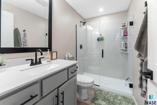 bathroom with vanity, toilet, wood-type flooring, and a shower with shower door