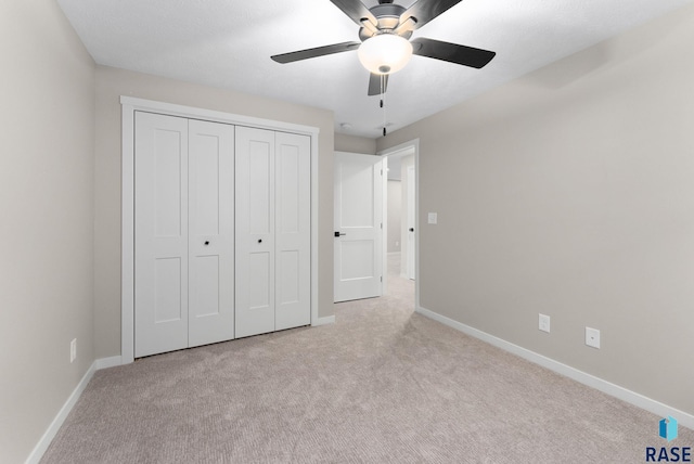 unfurnished bedroom with light carpet, a closet, and ceiling fan