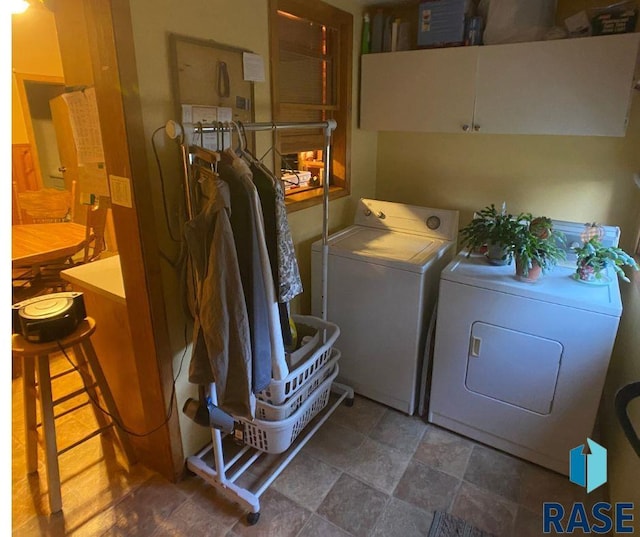 clothes washing area featuring cabinets and independent washer and dryer