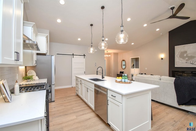 kitchen featuring white cabinets, a barn door, a kitchen island with sink, and sink