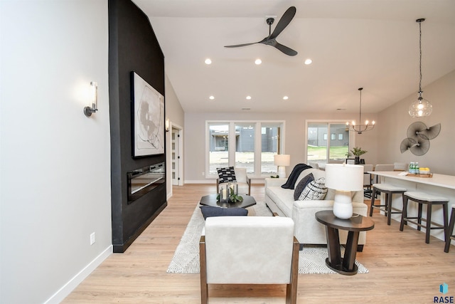 living room featuring ceiling fan with notable chandelier, light wood-type flooring, and lofted ceiling