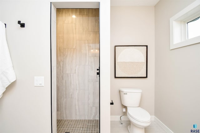 bathroom featuring tile patterned flooring, a tile shower, and toilet