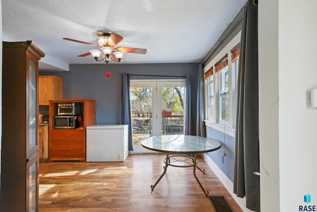 dining room featuring ceiling fan, a textured ceiling, and light hardwood / wood-style flooring