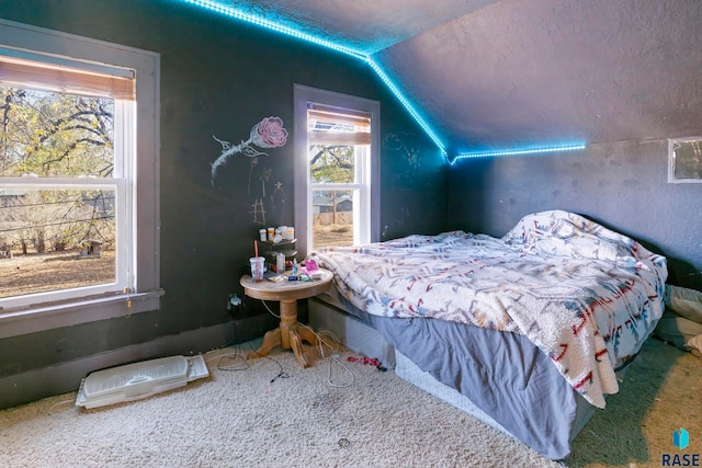 carpeted bedroom with a textured ceiling and vaulted ceiling