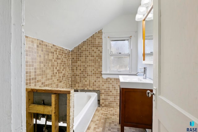 bathroom with tile walls, vanity, a bath, and lofted ceiling