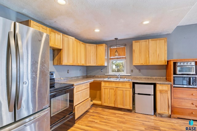 kitchen with sink, hanging light fixtures, stainless steel appliances, a textured ceiling, and light wood-type flooring